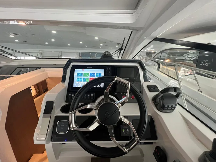 Sealine S390 Yacht Photos Pics 2022 Sealine S390 yacht cockpit with modern steering wheel and navigation display.