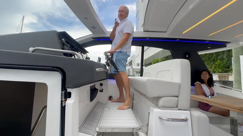 Moana & Malie Yacht Photos Pics Man steering 2025 Schaefer 375 yacht, woman seated, modern interior design.