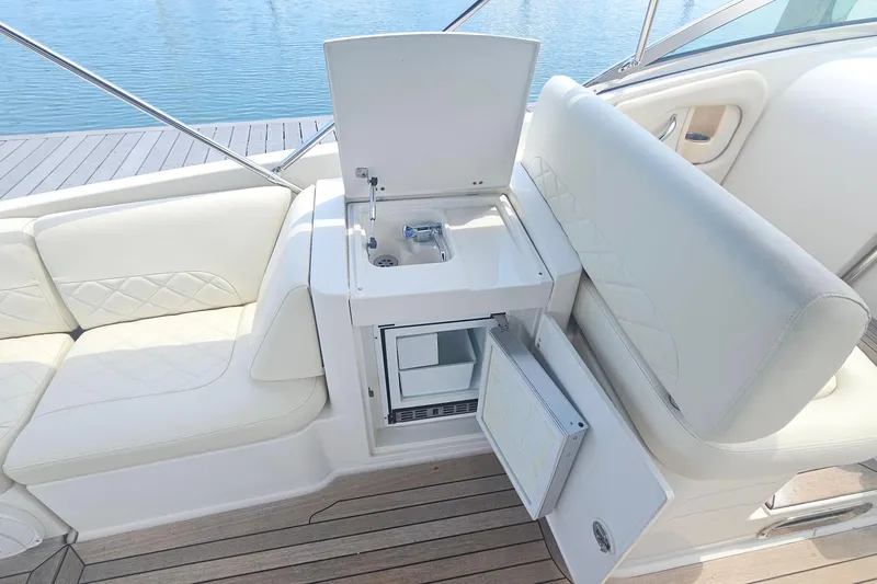 Taipan Yacht Photos Pics 2006 Chris-Craft Corsair 36 interior with white seating, sink, and mini fridge.