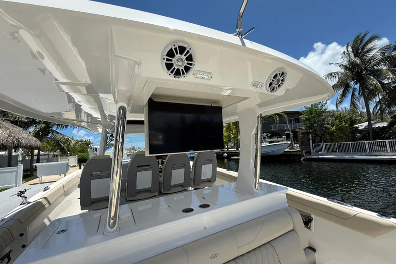  Yacht Photos Pics 2022 Regal 38 SAV boat interior with seating, TV, and speakers, docked by palm trees.