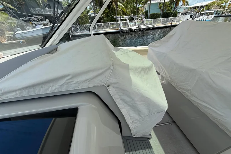  Yacht Photos Pics 2022 Regal 38 SAV boat interior with protective covers, docked near waterfront homes.