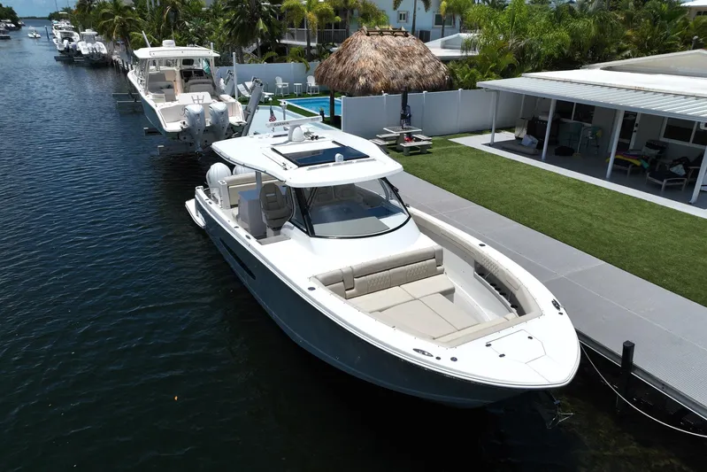 Yacht Photos Pics 2022 Regal 38 SAV boat docked by a waterfront home with lush greenery.