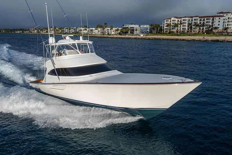 South Jersey Yacht Sales Demo Boat Yacht Photos Pics 2025 Viking 64 Convertible yacht cruising on open water near coastal buildings.