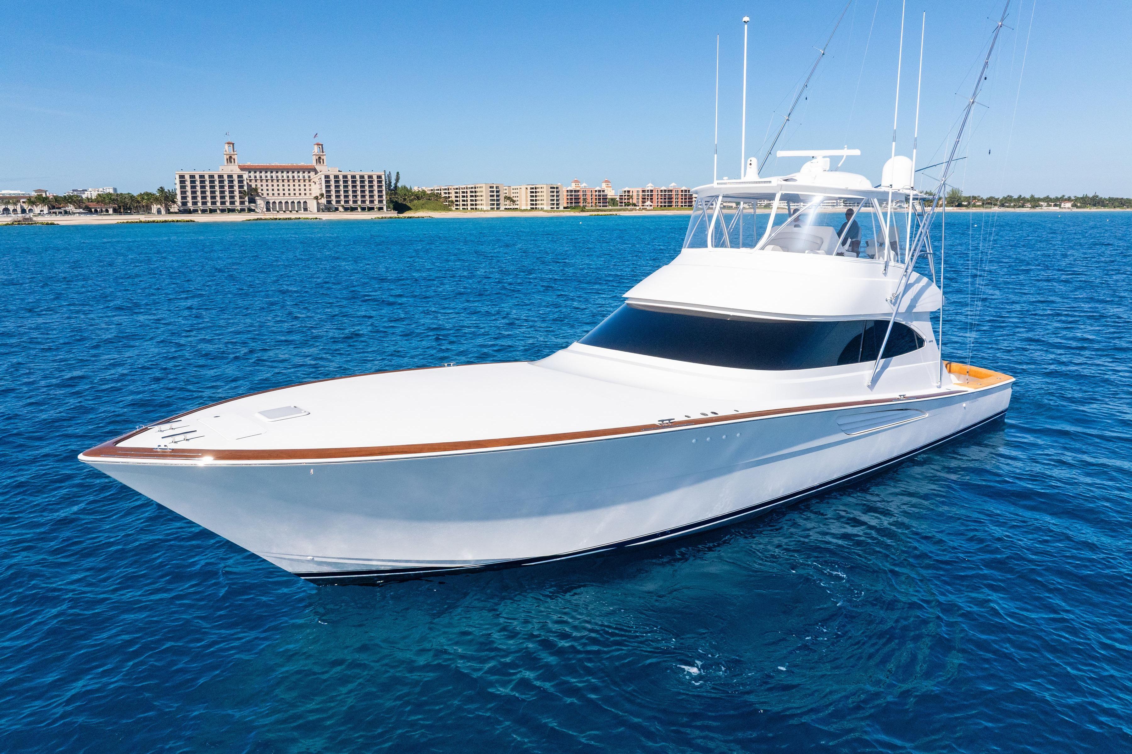 2025 Viking 64 Convertible yacht on clear blue ocean near coastal buildings.