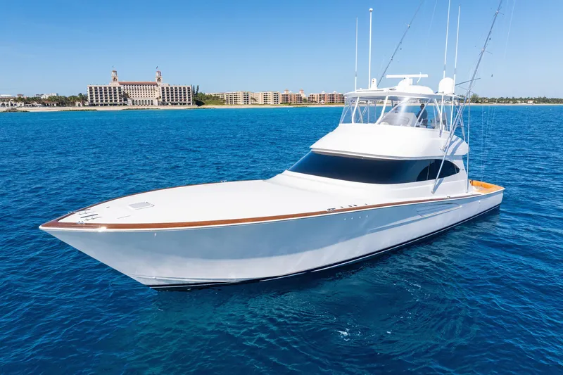  Yacht Photos Pics 2025 Viking 64 Convertible yacht on clear blue ocean near coastal buildings.