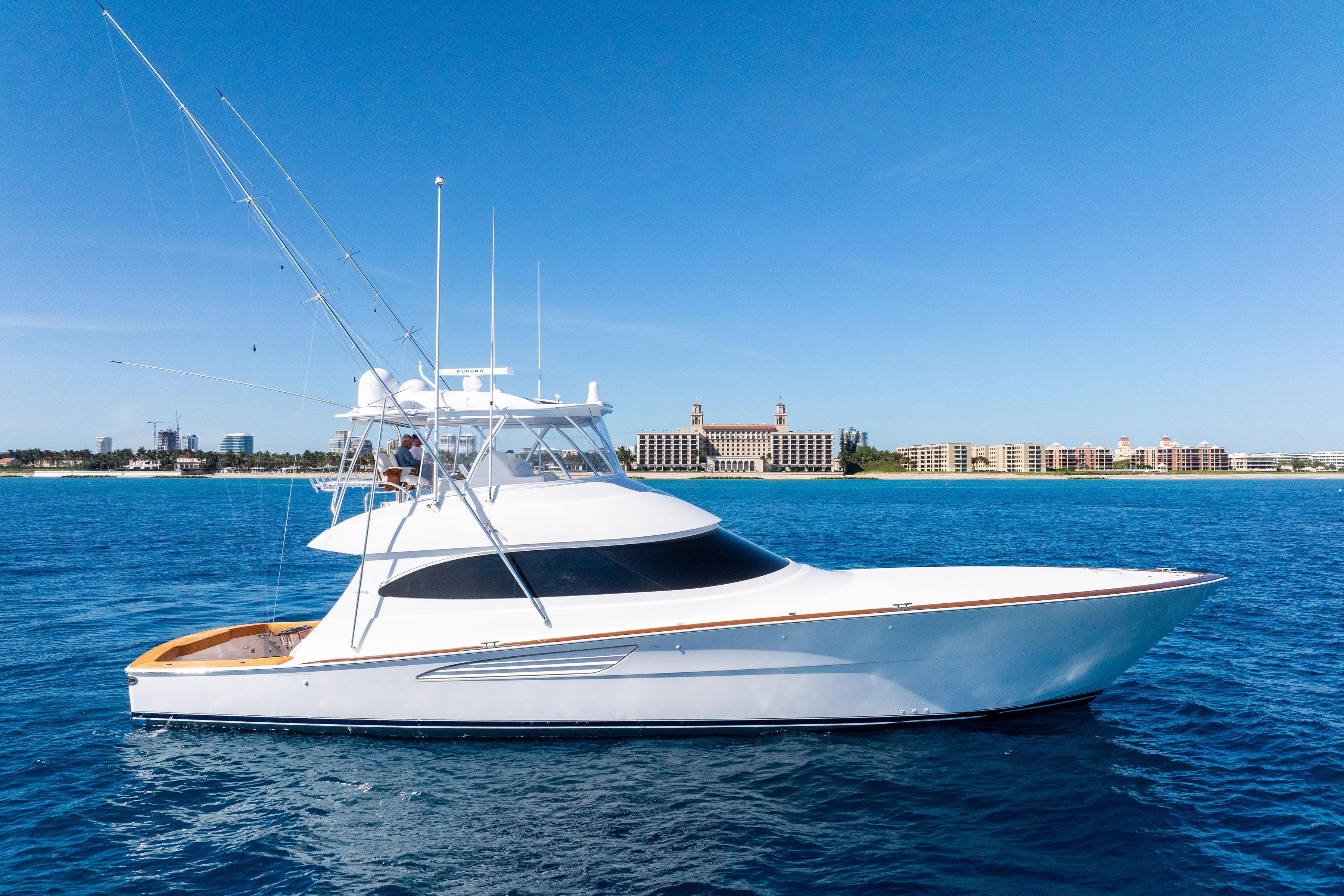 2025 Viking 64 Convertible yacht cruising on blue ocean near coastal cityscape.