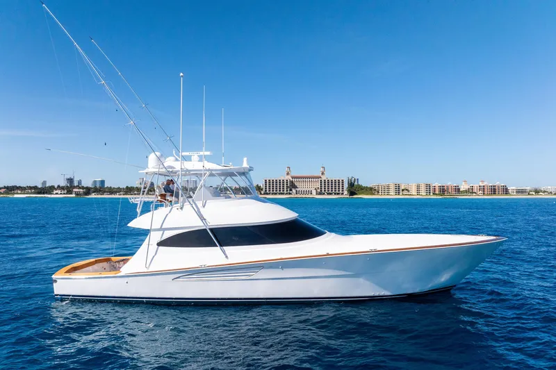  Yacht Photos Pics 2025 Viking 64 Convertible yacht cruising on blue ocean near coastal cityscape.