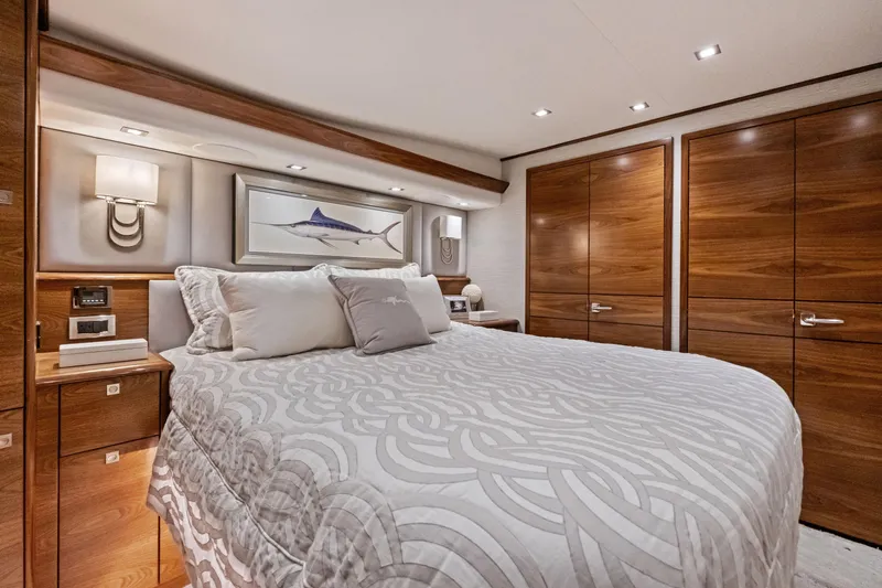  Yacht Photos Pics Luxurious bedroom interior of 2025 Viking 64 Convertible yacht with elegant wood finishes.