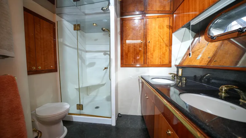 4 Princesses Yacht Photos Pics Luxurious bathroom in a 2002 Queenship 70 Baretta yacht with glass shower and wooden cabinets.