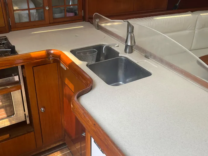 Argo Yacht Photos Pics 2004 Hunter 44 DS Deck Salon kitchen with sink, faucet, and wooden cabinetry.