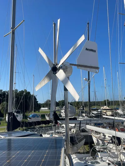 Argo Yacht Photos Pics Wind turbine on 2004 Hunter 44 DS Deck Salon sailboat, with solar panels and marina background.