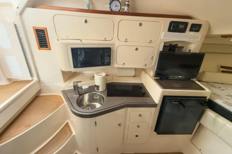  Yacht Photos Pics 2006 Grady-White Express 330 boat interior with kitchenette, sink, microwave, and storage cabinets.