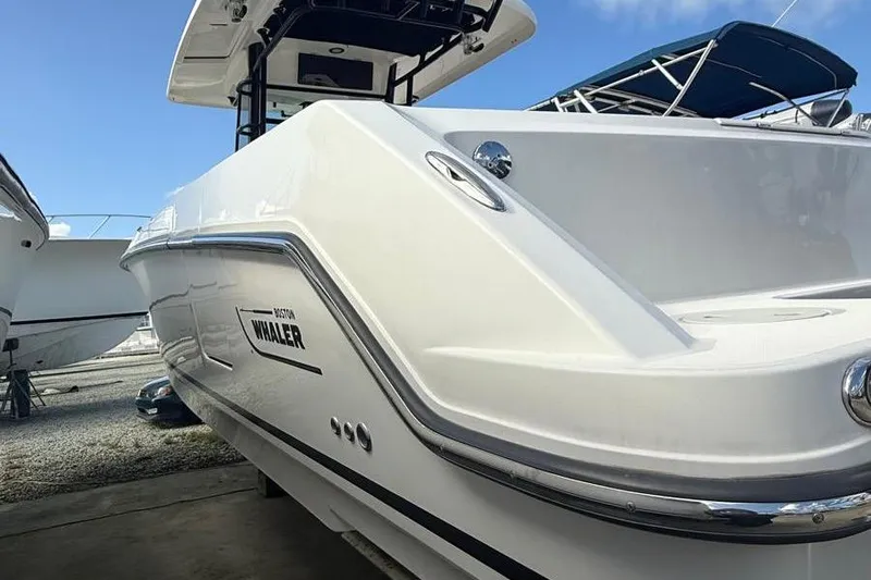  Yacht Photos Pics 2023 Boston Whaler 330 Outrage boat, sleek design, docked under clear blue sky.