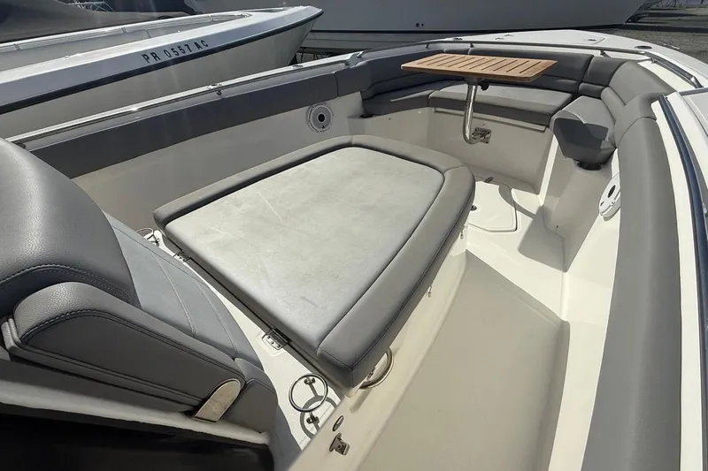  Yacht Photos Pics 2023 Boston Whaler 330 Outrage interior with cushioned seating and wooden table.