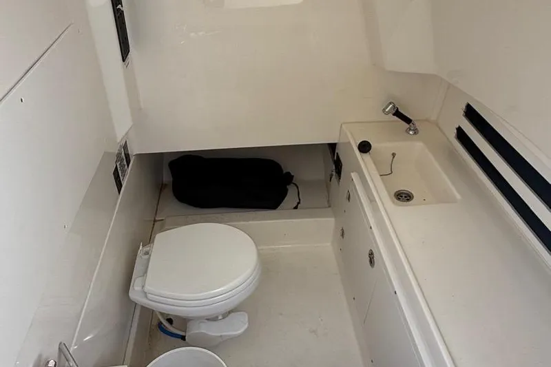  Yacht Photos Pics 2023 Boston Whaler 330 Outrage cabin with toilet and sink, featuring compact design.