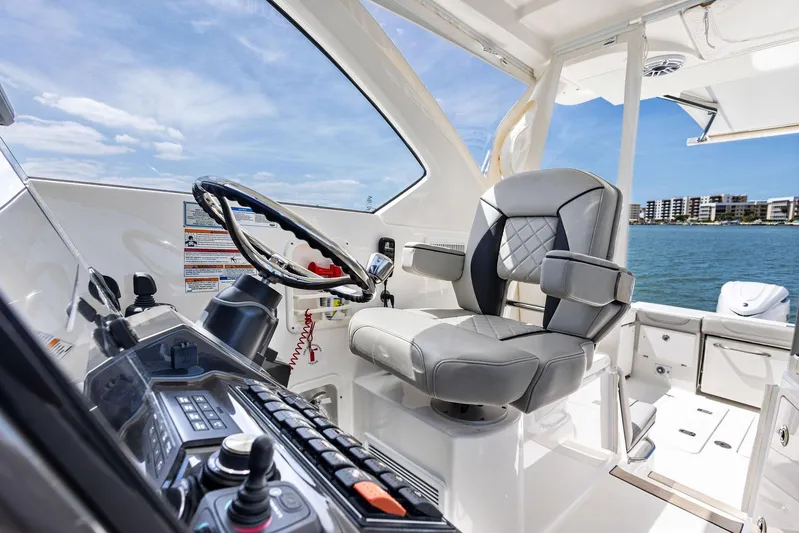 No Name Yacht Photos Pics 2025 Pursuit OS 355 Offshore boat cockpit with modern steering and controls, overlooking water and skyline.