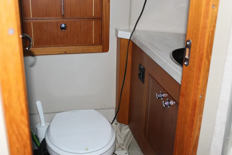  Yacht Photos Pics 2016 Aspen B100 boat bathroom with wooden cabinets and compact toilet.
