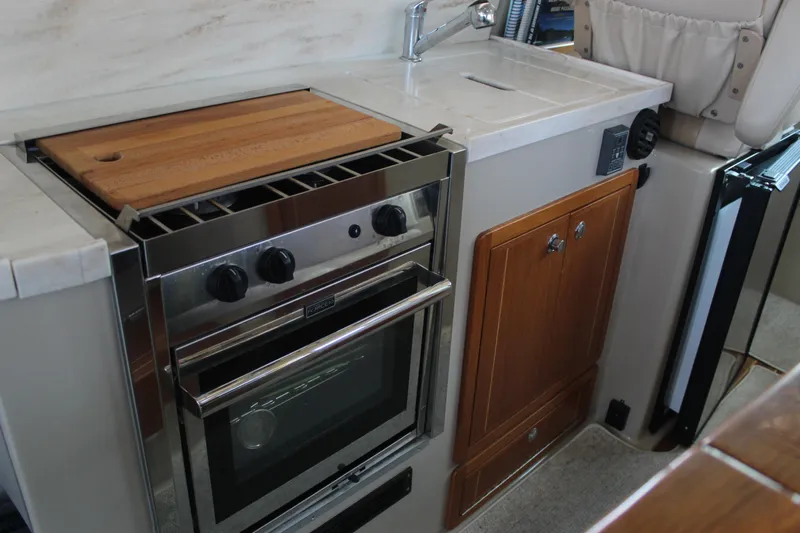  Yacht Photos Pics Compact kitchen in 2016 Aspen B100 with stove, sink, and wooden cabinetry.