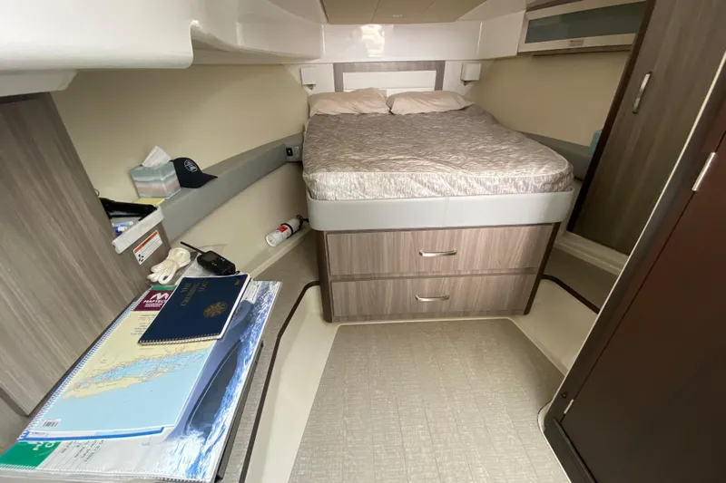 Camelot Yacht Photos Pics 2022 Regal 36 XO cabin interior with bed, storage, and navigation materials.