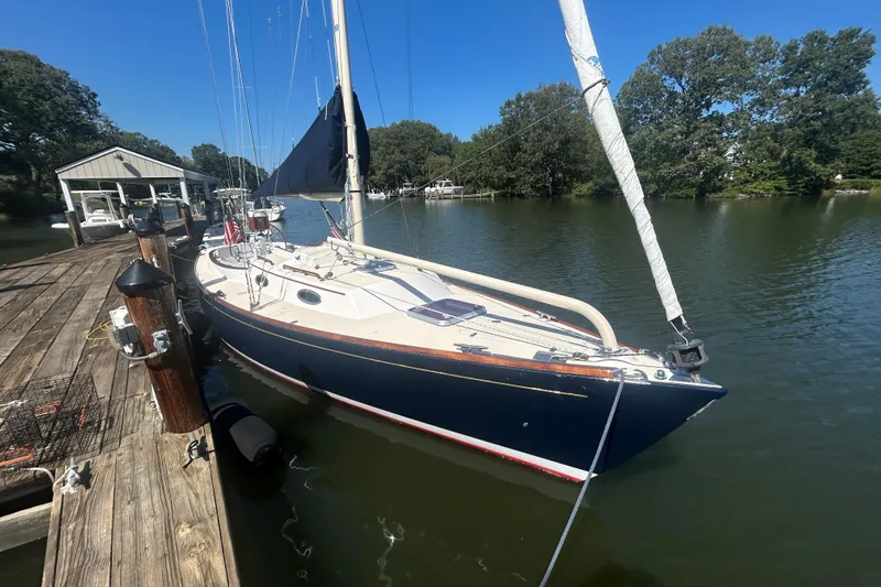  Yacht Photos Pics 2008 Alerion Express 33 sailboat docked on a sunny day, surrounded by trees.