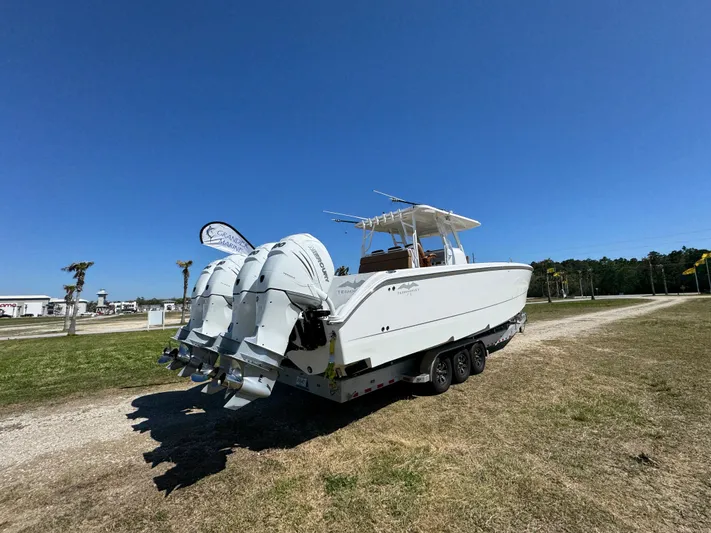  Yacht Photos Pics 2023 Invincible 37 Catamaran with triple outboard engines on a trailer, under clear blue sky.