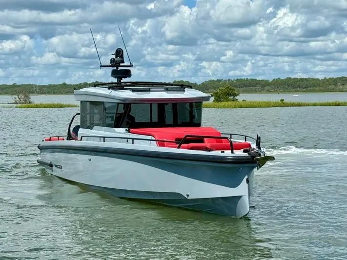  Yacht Photos Pics 2023 Axopar Shadow 900XC boat cruising on a scenic lake under a cloudy sky.