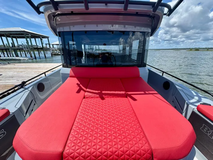  Yacht Photos Pics 2023 Axopar Shadow 900XC with red seating, docked by a scenic waterfront.