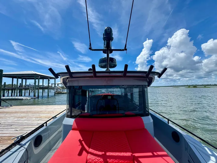  Yacht Photos Pics 2023 Axopar Shadow 900XC boat docked by the water under a clear blue sky.