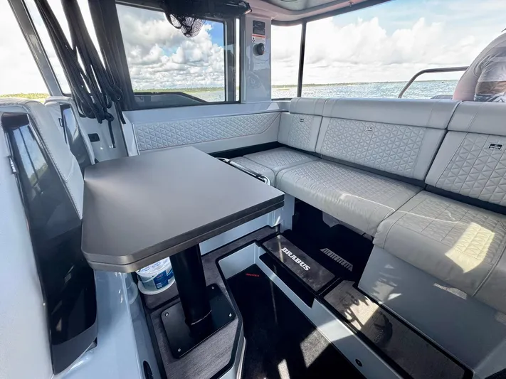  Yacht Photos Pics 2023 Axopar Shadow 900XC interior with modern seating and table, overlooking the ocean.