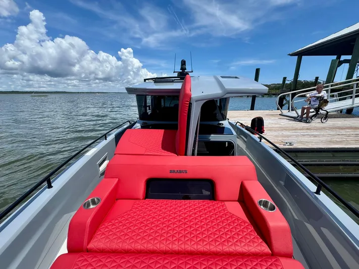  Yacht Photos Pics 2023 Axopar Shadow 900XC with red seating, docked by a scenic waterfront.