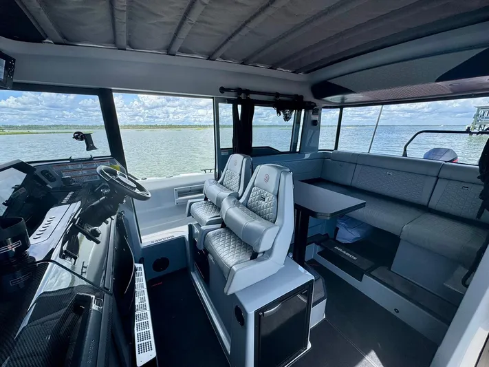  Yacht Photos Pics 2023 Axopar Shadow 900XC interior with modern seating and panoramic windows on the water.