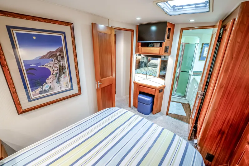 Second Chance Yacht Photos Pics Luxurious 1995 Viking 50 yacht interior with wood accents, striped bedding, and framed artwork.