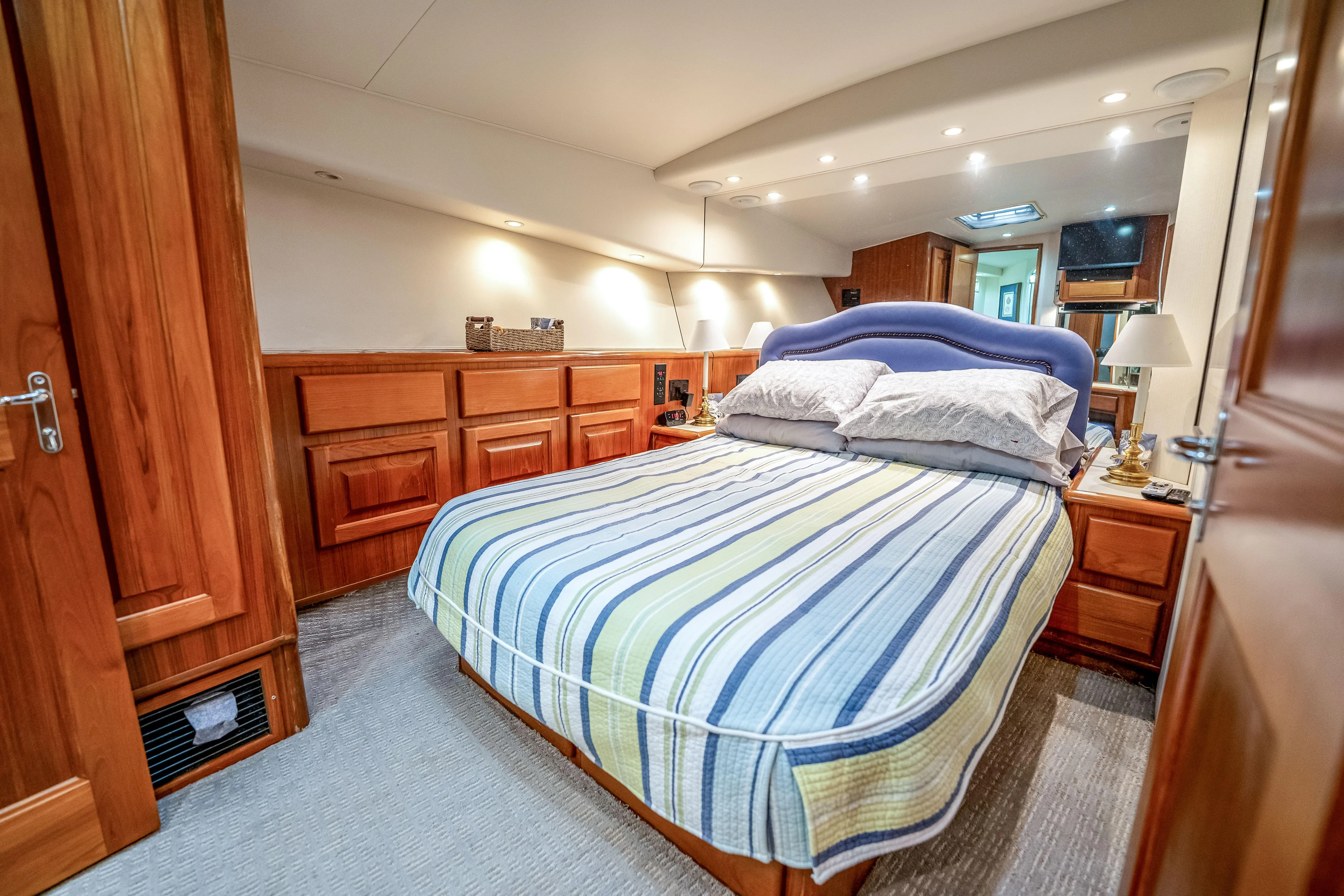 Second Chance Yacht Photos Pics Luxurious bedroom interior on a 1995 Viking 50 yacht, featuring wood paneling and striped bedding.