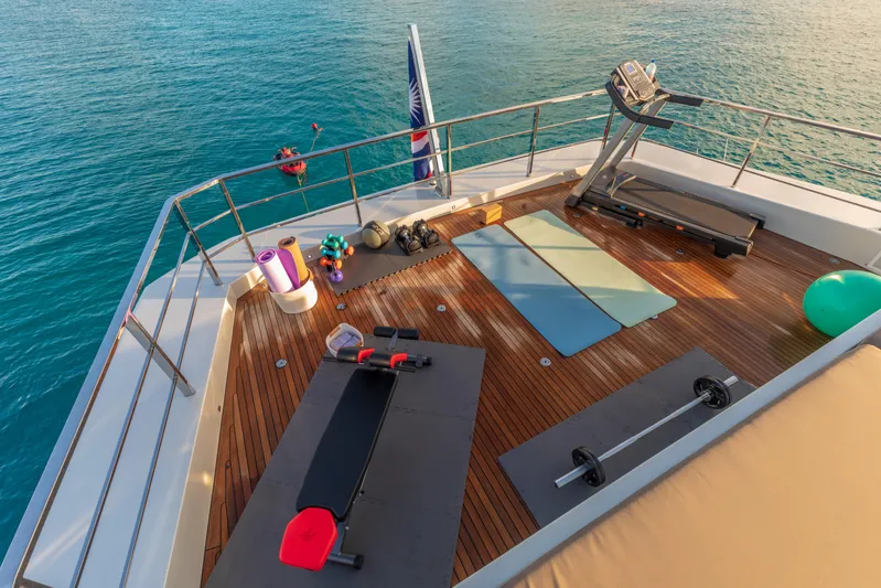 Safe Haven Yacht Photos Pics Outdoor gym on Admiral Custom yacht deck, featuring treadmill, mats, weights, overlooking ocean.