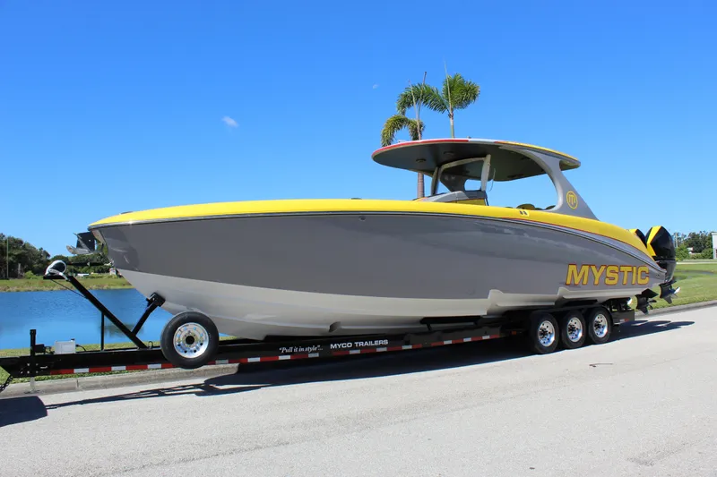  Yacht Photos Pics 2021 Mystic M4200 boat on trailer, yellow and gray design, parked near water.