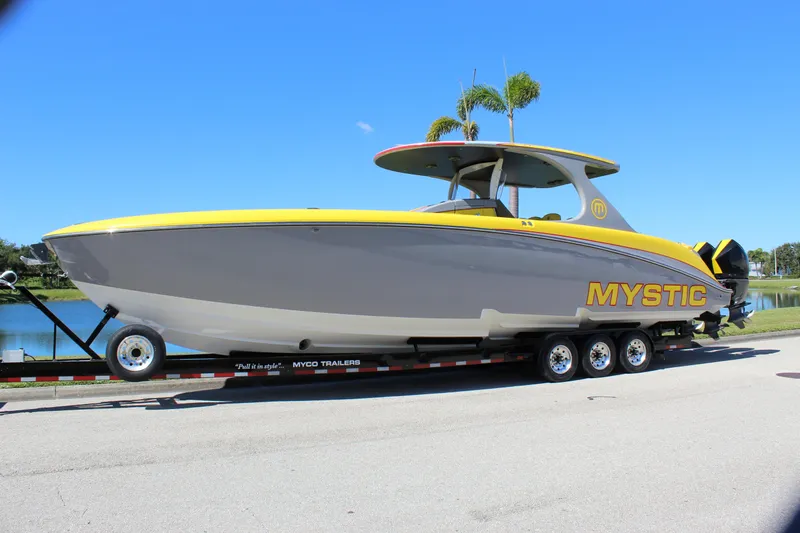  Yacht Photos Pics 2021 Mystic M4200 boat on trailer, yellow and gray design, parked near water.