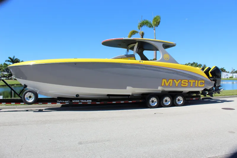  Yacht Photos Pics 2021 Mystic M4200 boat on trailer, yellow and gray design, parked near water.