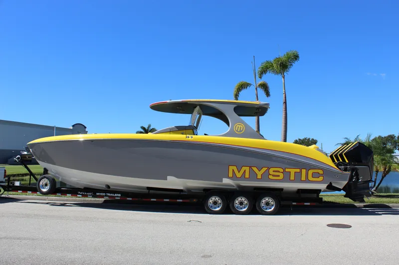  Yacht Photos Pics 2021 Mystic M4200 boat on trailer, yellow and gray design, palm trees in background.