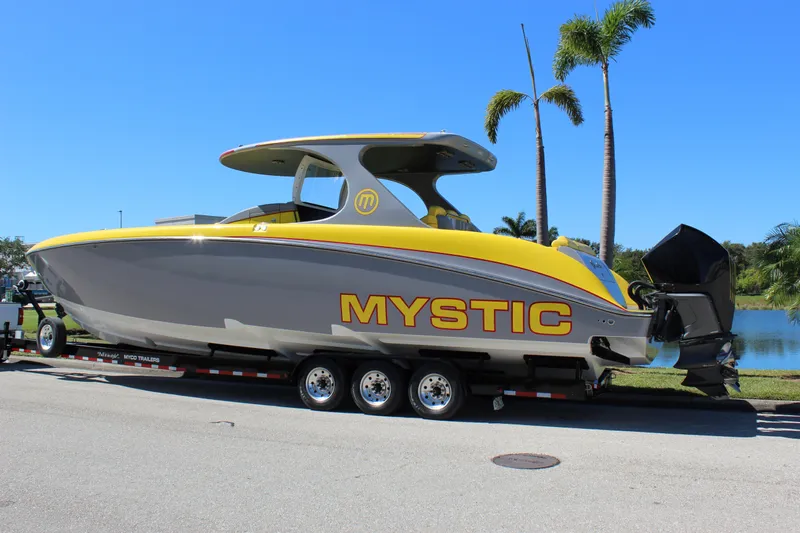  Yacht Photos Pics 2021 Mystic M4200 boat on trailer, yellow and gray design, palm trees in background.
