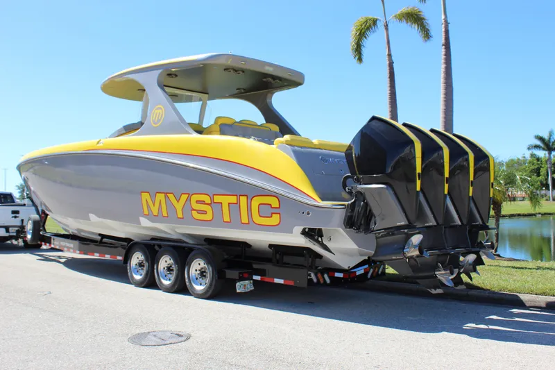  Yacht Photos Pics Yellow and gray 2021 Mystic M4200 boat on trailer, featuring four powerful outboard engines.