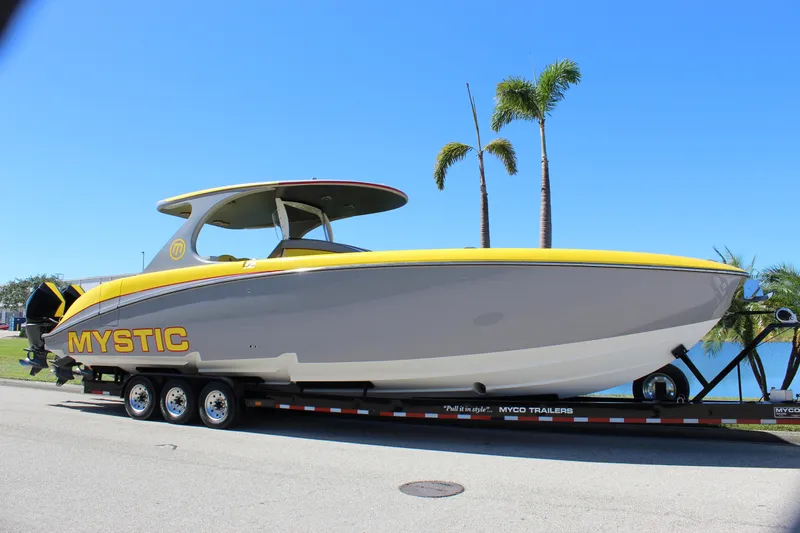  Yacht Photos Pics 2021 Mystic M4200 boat on trailer, yellow and gray design, palm trees in background.