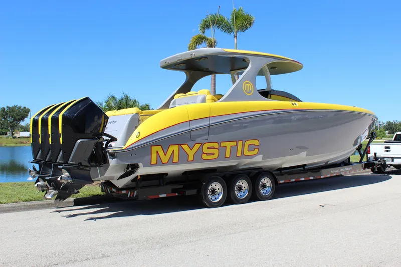  Yacht Photos Pics 2021 Mystic M4200 boat on trailer, yellow and gray design, parked near water.