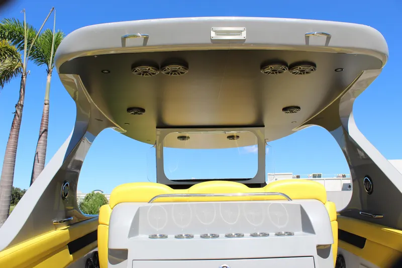 Yacht Photos Pics 2021 Mystic M4200 boat interior with yellow seating and overhead speakers, under clear blue sky.