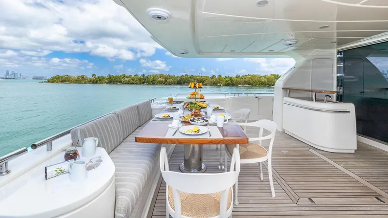 Hoya Saxa Yacht Photos Pics Luxurious dining setup on 2013 Ferretti Yachts 870 FLYBRIDGE, overlooking serene waters and lush greenery.