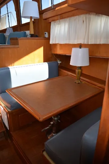 Aloha Yacht Photos Pics 1988 Marine Trader 47 Tradewinds interior with wooden dining table and blue cushioned seating.