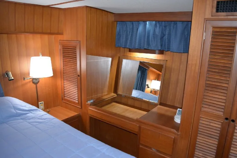 Aloha Yacht Photos Pics 1988 Marine Trader 47 Tradewinds cabin with wooden interior, mirror, and blue curtains.