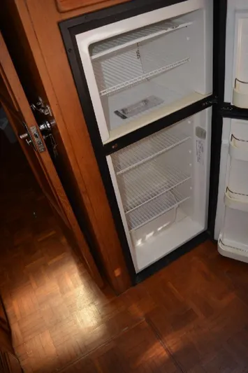 Aloha Yacht Photos Pics Empty refrigerator inside 1988 Marine Trader 47 Tradewinds yacht, wooden floor visible.