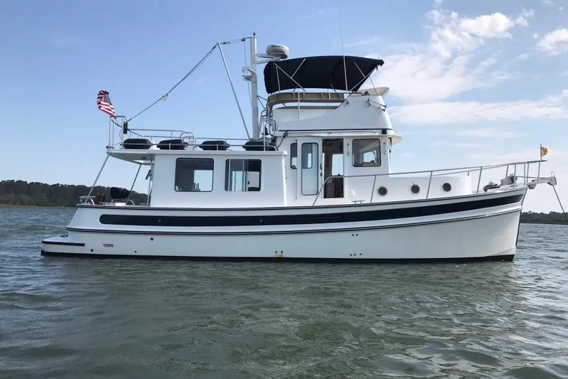 Egret Yacht Photos Pics 2005 Nordic Tug 37 Flybridge on calm water, featuring classic design and American flag.