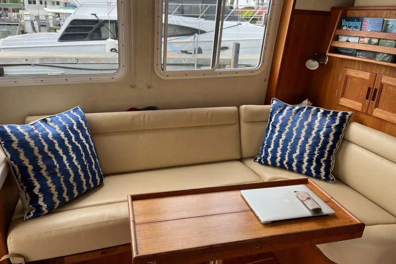 Egret Yacht Photos Pics Cozy interior of 2005 Nordic Tug 37 Flybridge featuring an L-shaped Ultraleather sofa with blue cushions and Teak table.