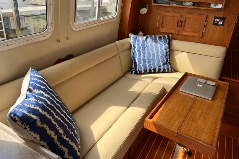Egret Yacht Photos Pics 2005 Nordic Tug 37 Flybridge interior with beige Ultraleather sofa, blue cushions, and wooden table.